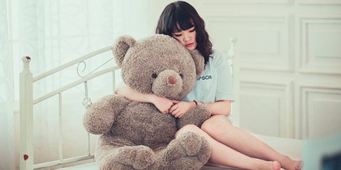 sad depressed hugging teddy bear in isolation