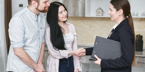 A real estate agent shaking hands with her client couple