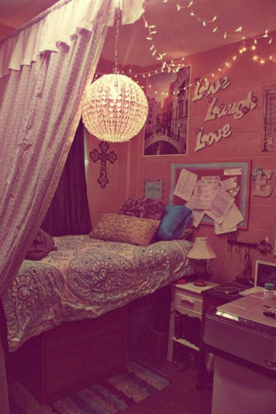 An image of a pink, pattern filled dorm room with a disco ceiling light.