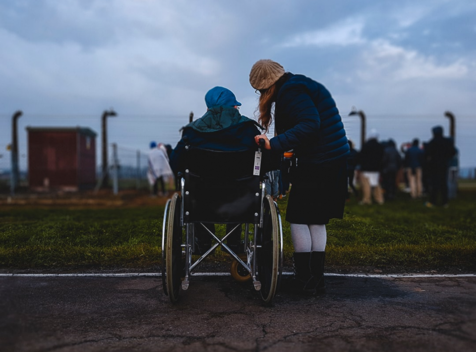 Person sitting in wheelchair with person standing beside them