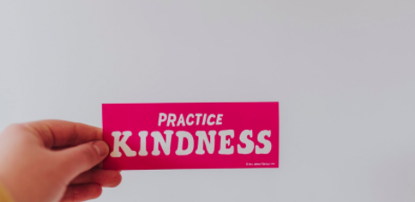 a hand holds a card that reads practice kindness