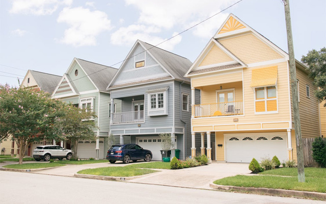 Three pastel-coloured homes on a quiet neighbourhood street - House