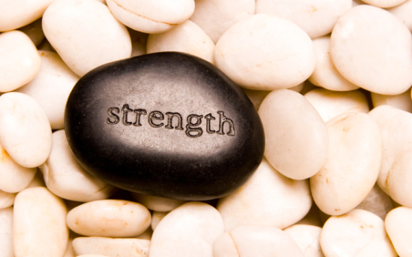a black polished stone with the word strength etched on it among smaller cream stones